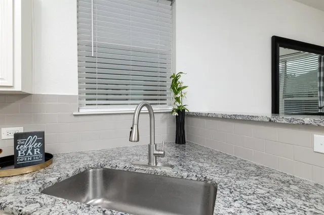a kitchen with a granite countertop sink and a window