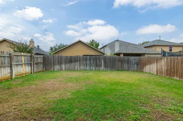 a view of a backyard with a garden and wooden fence