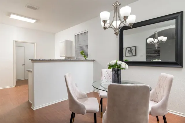 a dining room with wooden floor a chandelier a wooden table and chairs