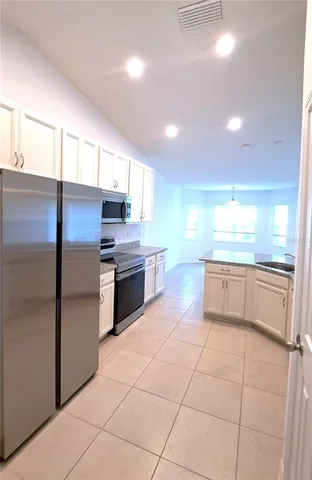 a large kitchen with a large counter top stainless steel appliances and cabinets