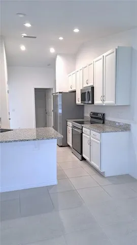 a large kitchen with stainless steel appliances granite countertop a stove a sink and a refrigerator