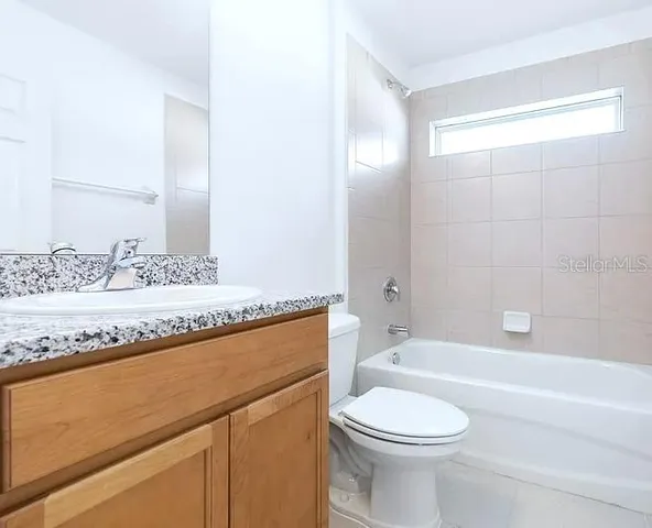 a bathroom with a granite countertop sink a toilet and bathtub
