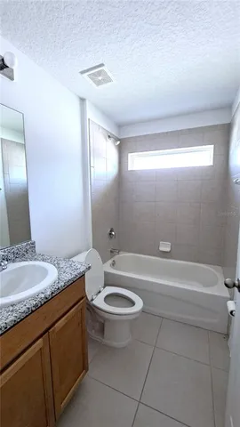 a bathroom with a granite countertop sink a toilet a mirror and bathtub