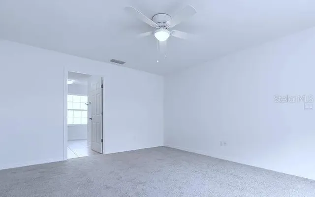 an empty room with a window and a ceiling fan