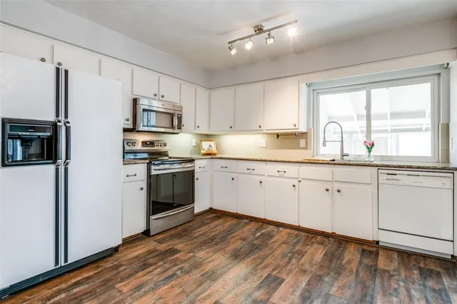 a kitchen with granite countertop white cabinets and white stainless steel appliances