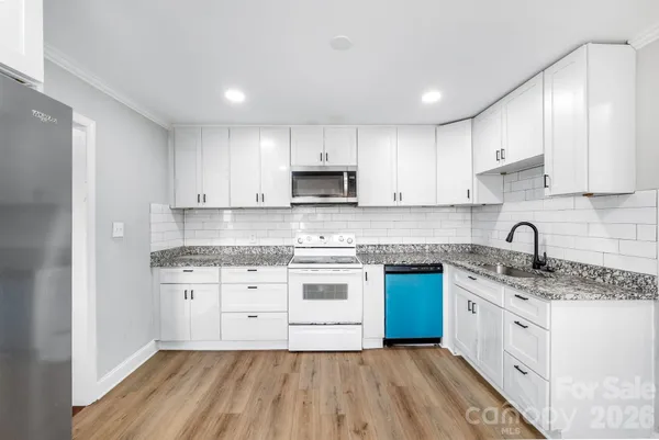 a kitchen with granite countertop white cabinets sink and stainless steel appliances