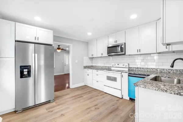 a kitchen with stainless steel appliances granite countertop a refrigerator stove microwave and sink