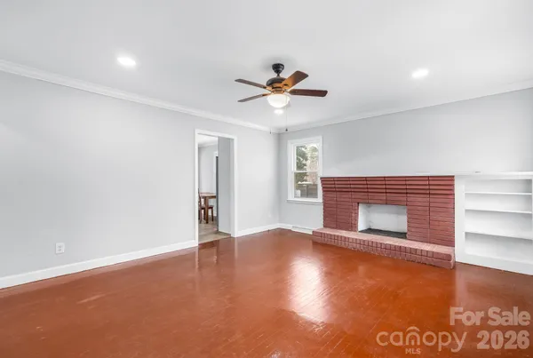 a view of an empty room with a window and wooden floor