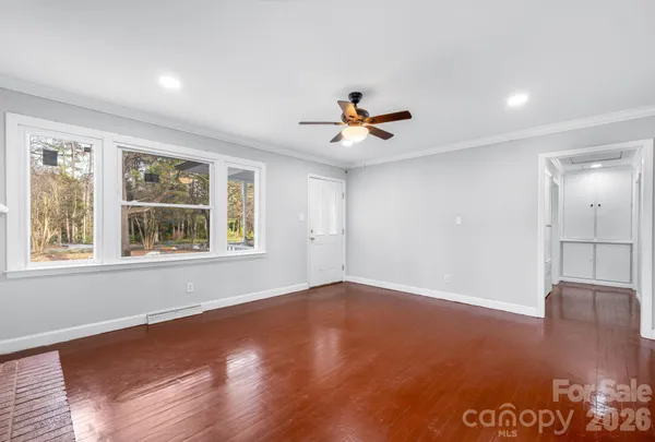 a view of an empty room with a window and wooden floor