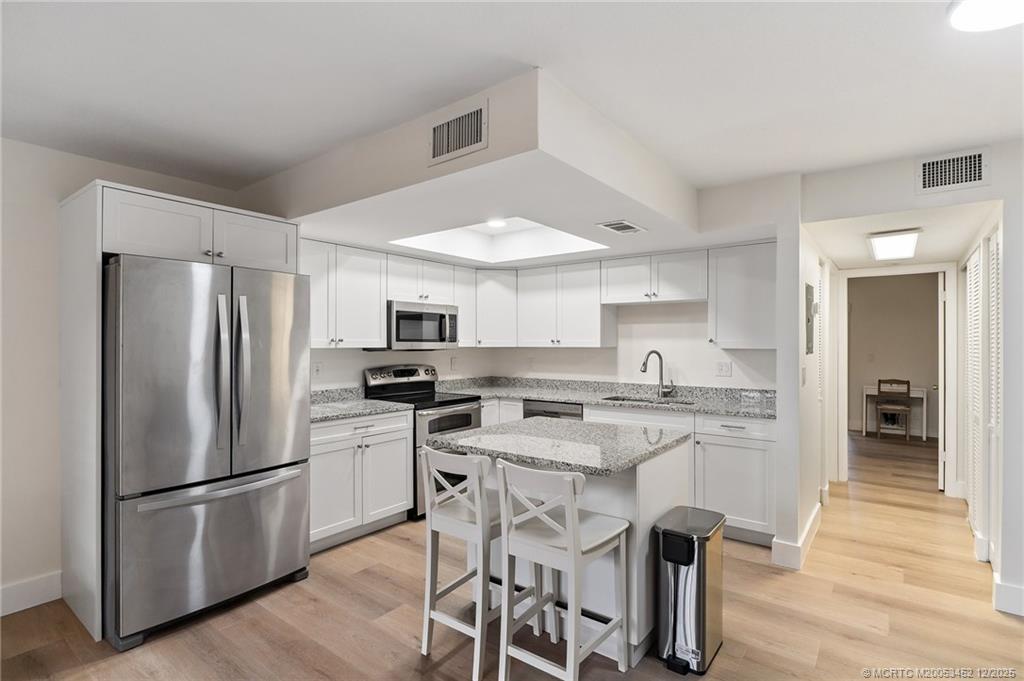 511 Southwest South River Drive, Unit 104 Stuart, FL 34997 - Photo 18 of 61 a kitchen with stainless steel appliances a refrigerator a stove a sink a dining table and chairs