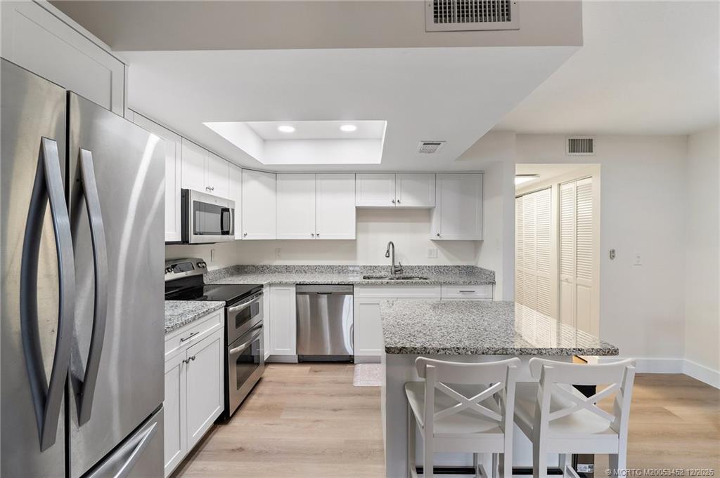 511 Southwest South River Drive, Unit 104 Stuart, FL 34997 - Photo 19 of 61 a kitchen with stainless steel appliances granite countertop a stove refrigerator sink and cabinets