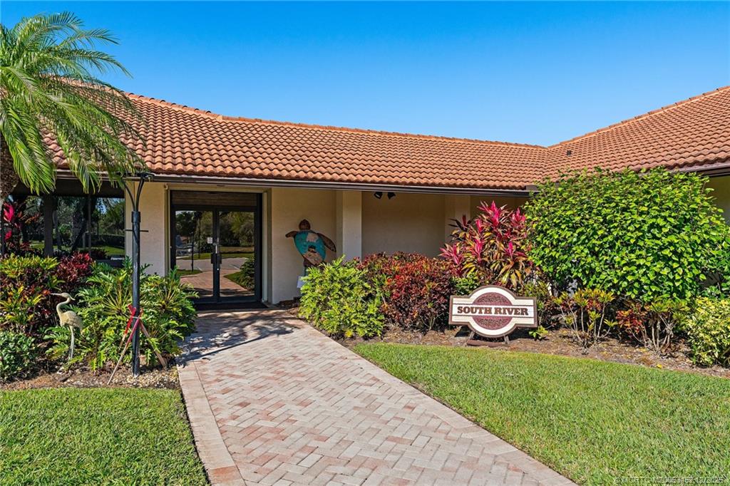 511 Southwest South River Drive, Unit 104 Stuart, FL 34997 - Photo 40 of 61 a front view of a house with a yard and potted plants