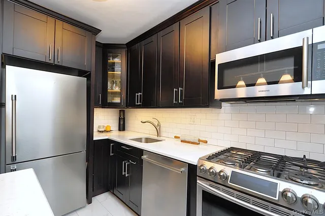 a kitchen with stainless steel appliances a refrigerator a sink and wooden cabinets