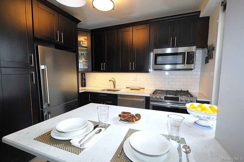 281 Garth Road, Unit A5L Scarsdale, NY 10583 - Photo 16 of 46 a kitchen with a refrigerator a stove a sink and a dining table with wooden floor