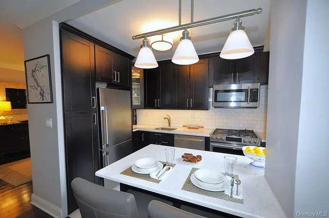 a living room with stainless steel appliances kitchen island a table and chairs