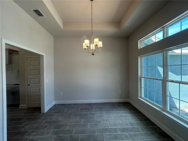 a view of a livingroom with a chandelier fan and windows