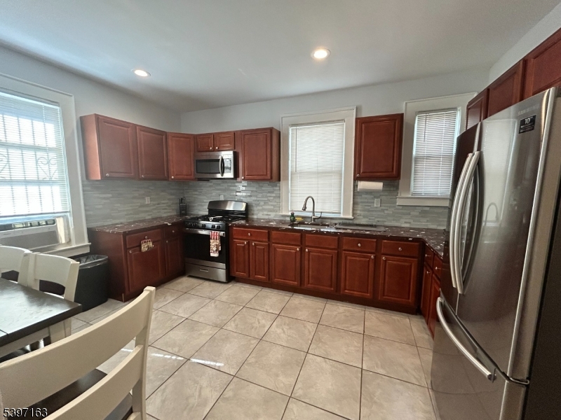 142 Mapes Avenue Newark, NJ 07112 - Photo 7 of 10 a kitchen with stainless steel appliances granite countertop a refrigerator sink and wooden cabinets