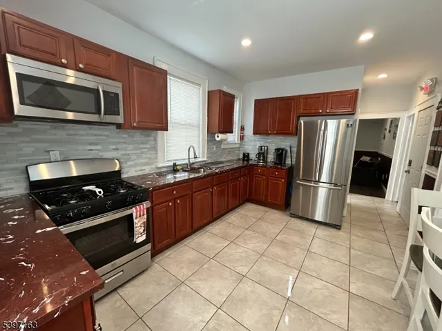a kitchen with stainless steel appliances granite countertop a stove a sink dishwasher a refrigerator and a microwave