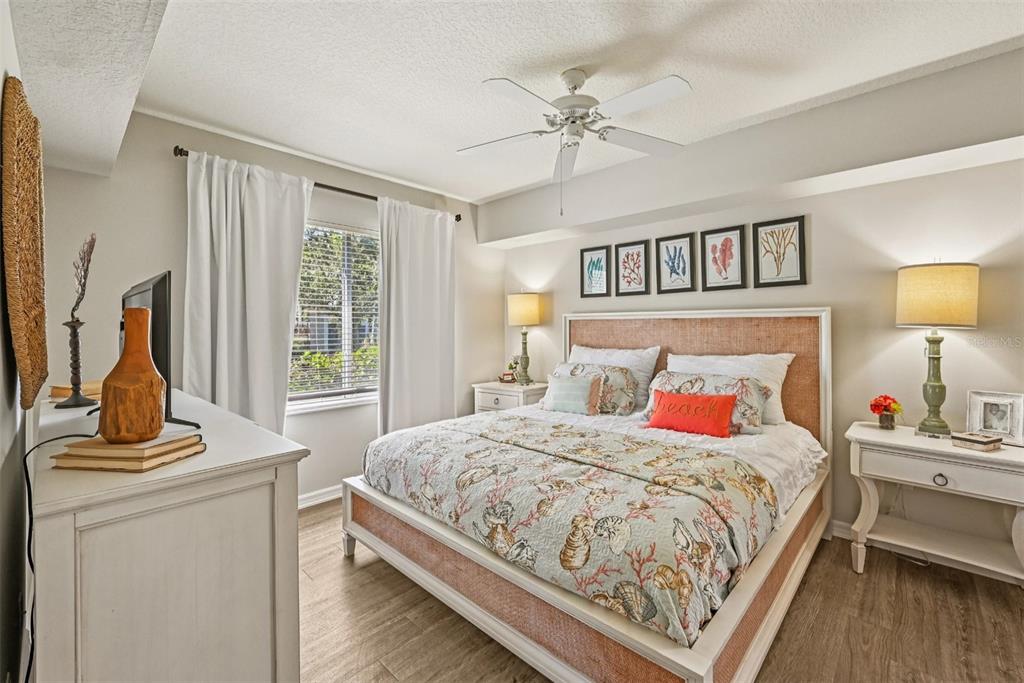 1010 Northwest Fresco Way, Unit 1B01206 Stuart, FL 34994 - Photo 13 of 47 a bedroom with a bed a dresser and wooden floor