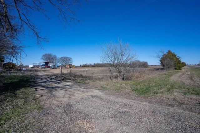 a view of dirt field with large trees