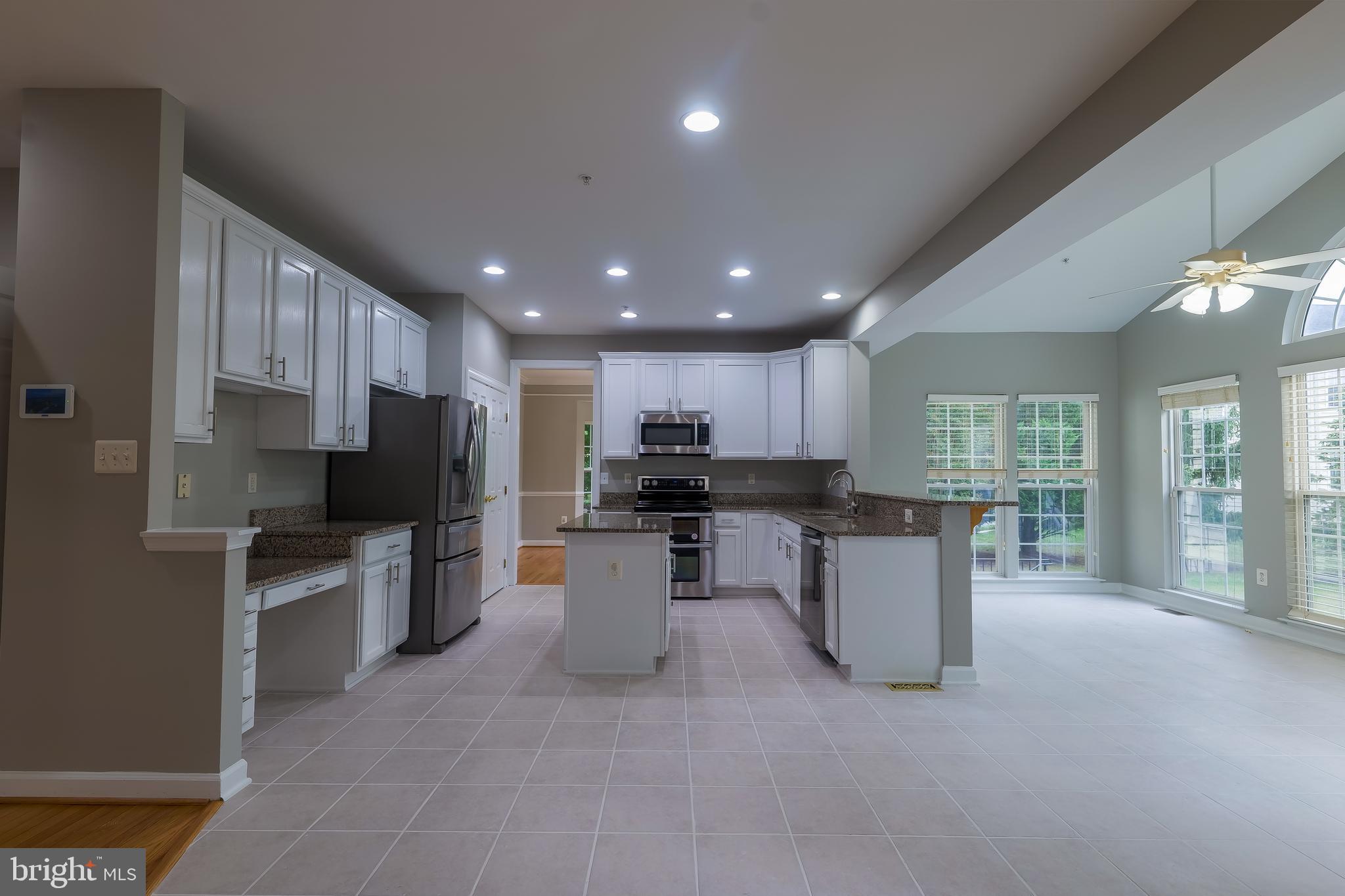 7709 Killbarron Drive Laurel, MD 20707 - Photo 39 of 79 a kitchen with stainless steel appliances kitchen island granite countertop a refrigerator oven a sink dishwasher a dining table and chairs with wooden floor