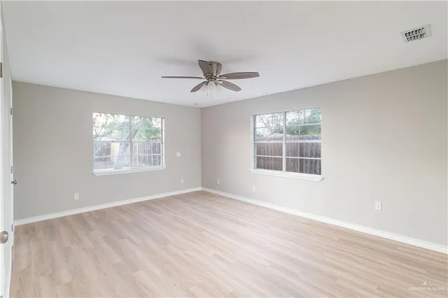 a view of an empty room with a window and wooden floor
