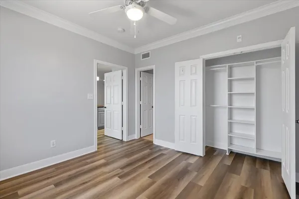 an empty room with wooden floor closet and windows