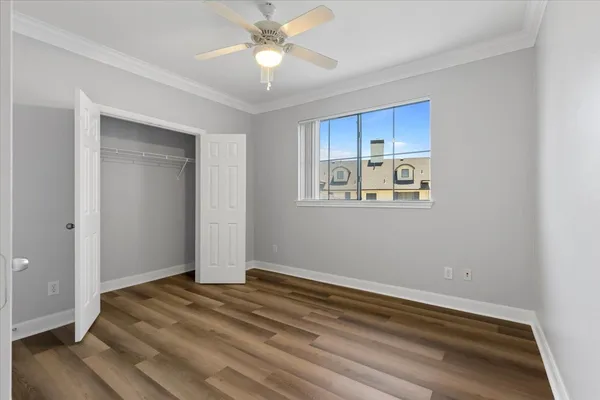 a view of empty room with wooden floor and fan