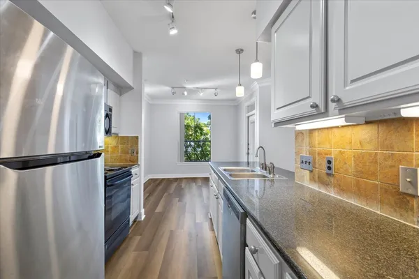 a kitchen with stainless steel appliances granite countertop a refrigerator a sink and a counter space