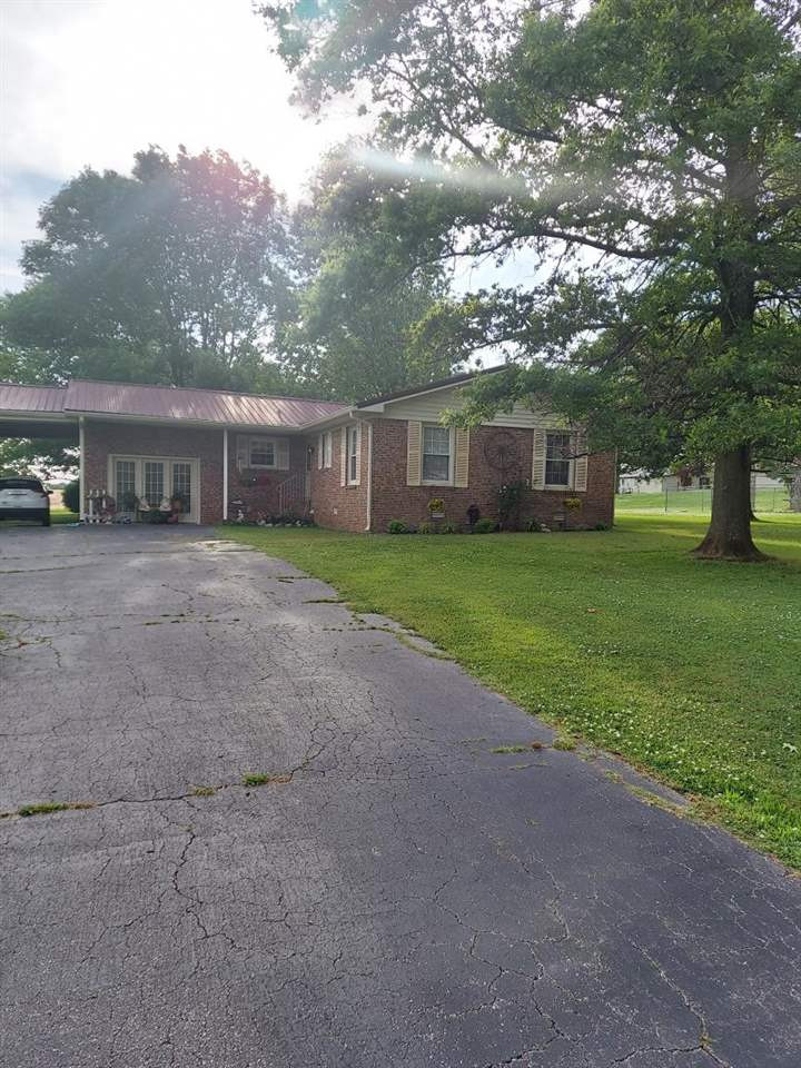 a view of a house with a yard and large trees