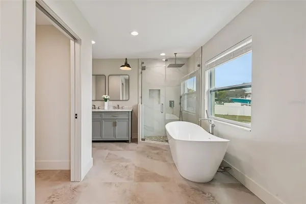 a bathroom with a white tub a sink and a window