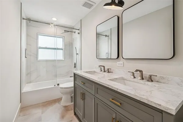 a bathroom with a granite countertop sink mirror vanity bathtub and toilet