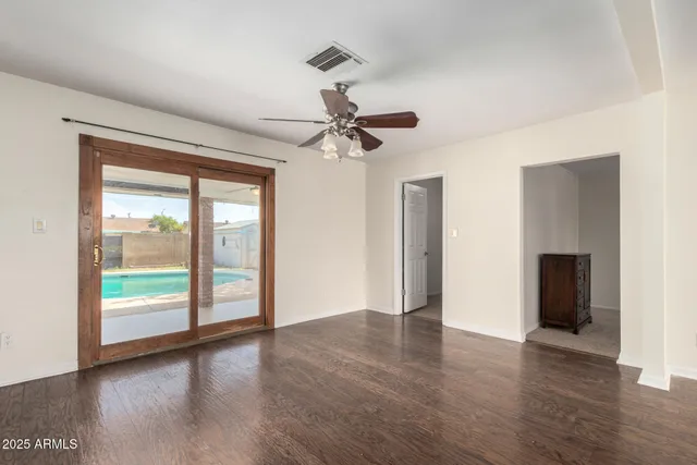 an empty room with wooden floor fan and windows