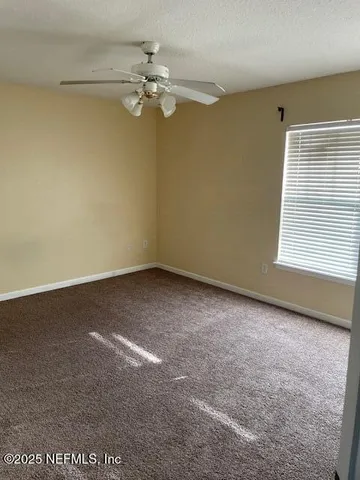 en empty room with windows and chandelier fan