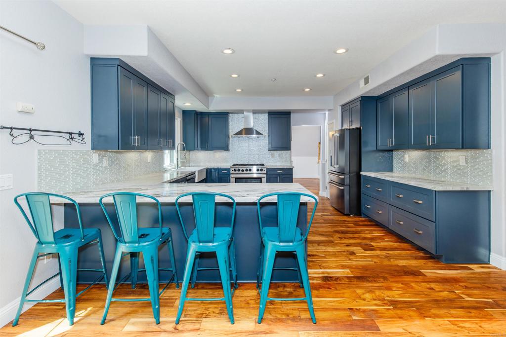 24427 Novato Place Ramona, CA 92065 - Photo 25 of 54 a kitchen with stainless steel appliances granite countertop a sink a stove a kitchen island with chairs and refrigerator