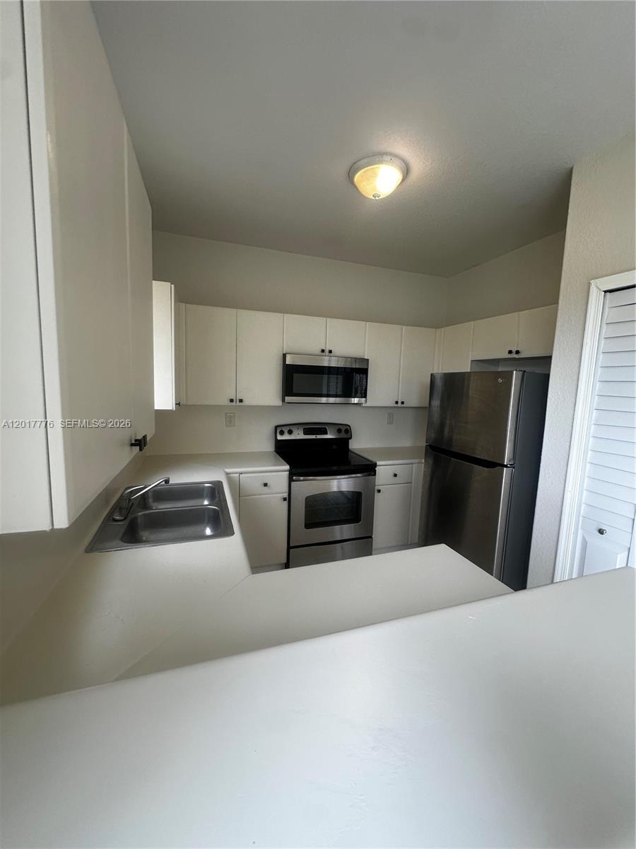 2907 Southeast 15th Road, Unit 67 Homestead, FL 33035 - Photo 5 of 25 a kitchen with granite countertop a refrigerator and a sink