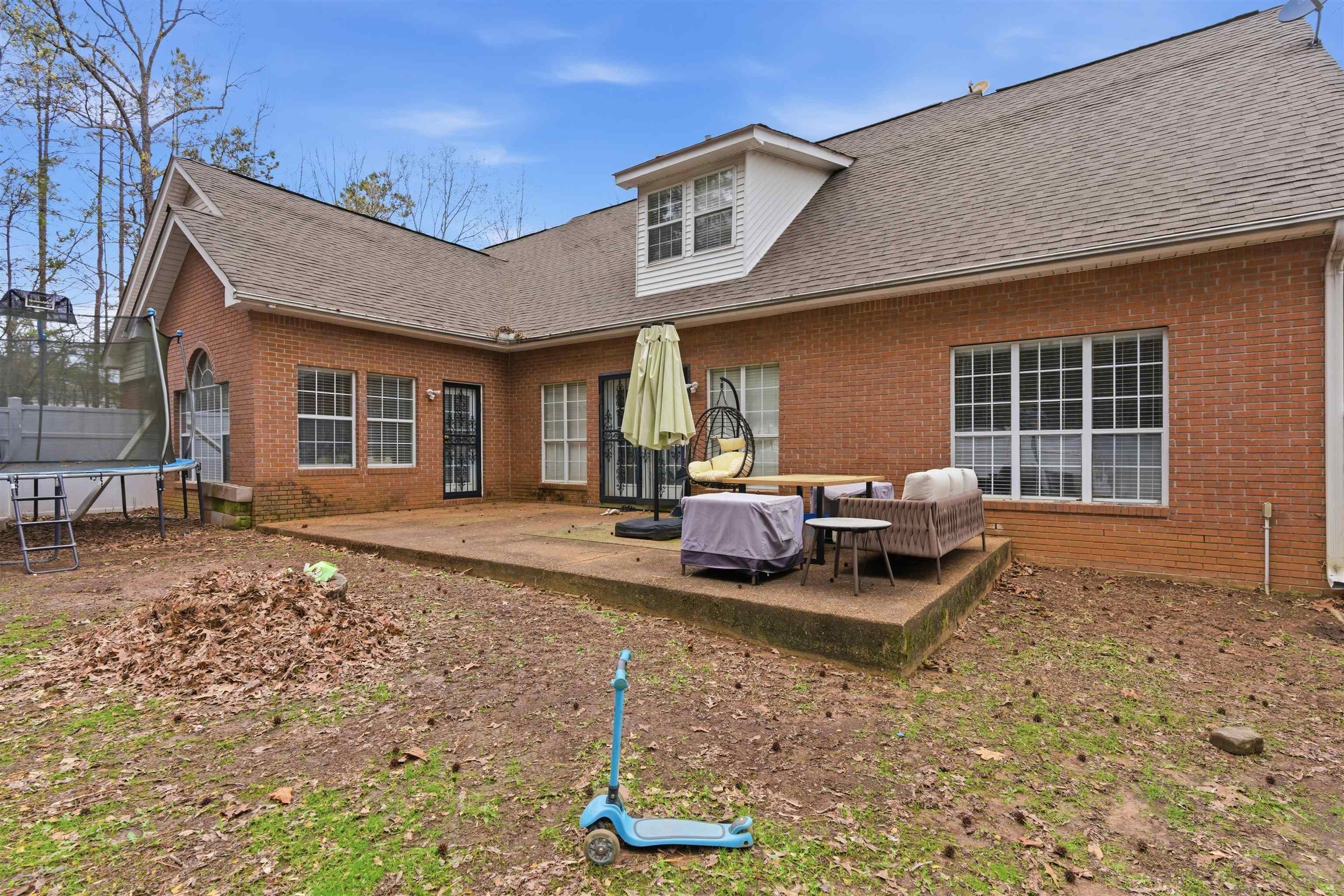 915 Cliffview Road Bolivar, TN 38008 - Photo 33 of 35 Rear view of house with a trampoline, brick siding, a shingled roof, a patio, and an outdoor living space