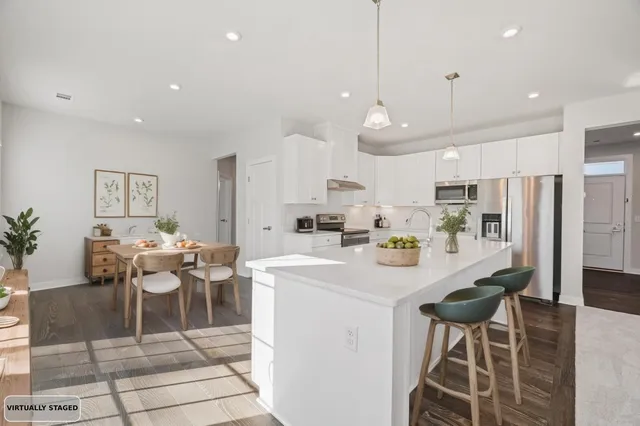 a kitchen with stainless steel appliances kitchen island granite countertop a table chairs and a refrigerator