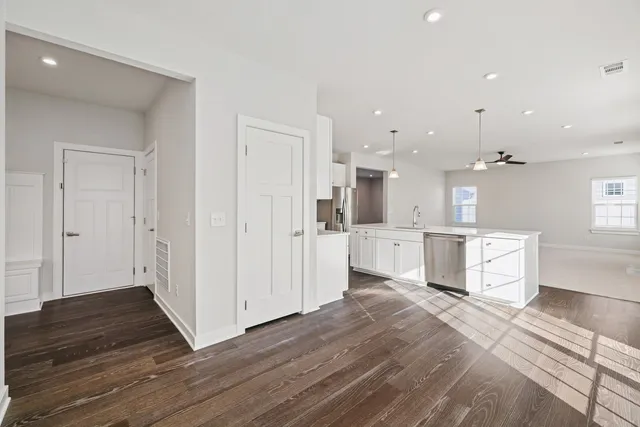 a large white kitchen with a refrigerator a sink dishwasher and a stove with wooden floor