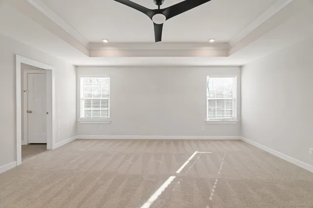 an empty room with windows and ceiling fan