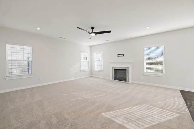 an empty room with windows and fireplace