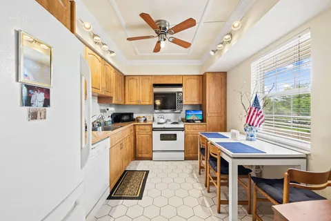 a kitchen with a stove a sink dishwasher a dining table and chairs with wooden floor
