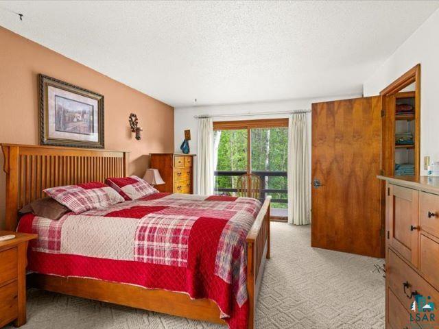 3616 Lavaque Road Hermantown, MN 55811 - Photo 32 of 43 Bedroom featuring wood-finish bed frame, light-colored walls, patterned carpeting, and sliding glass door leading to an outdoor balcony