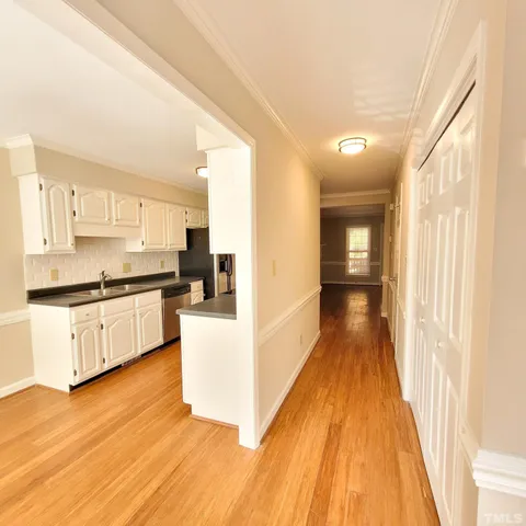 a large white kitchen with kitchen island a sink wooden floor and stainless steel appliances