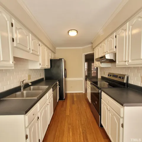 a kitchen with stainless steel appliances a sink dishwasher a refrigerator a stove top oven a counter space and cabinets
