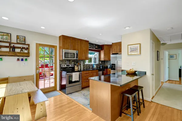a living room with stainless steel appliances furniture a flat screen tv and a refrigerator