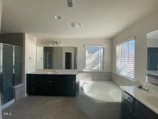a spacious bathroom with a double vanity sink toilet mirror and bathtub