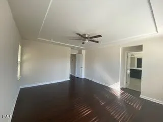 an empty room with wooden floor cabinet and windows