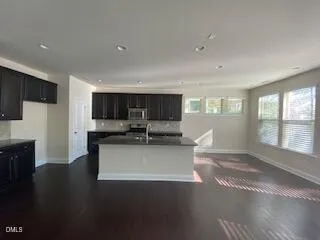 a view of a kitchen with kitchen island a sink wooden floor and a window