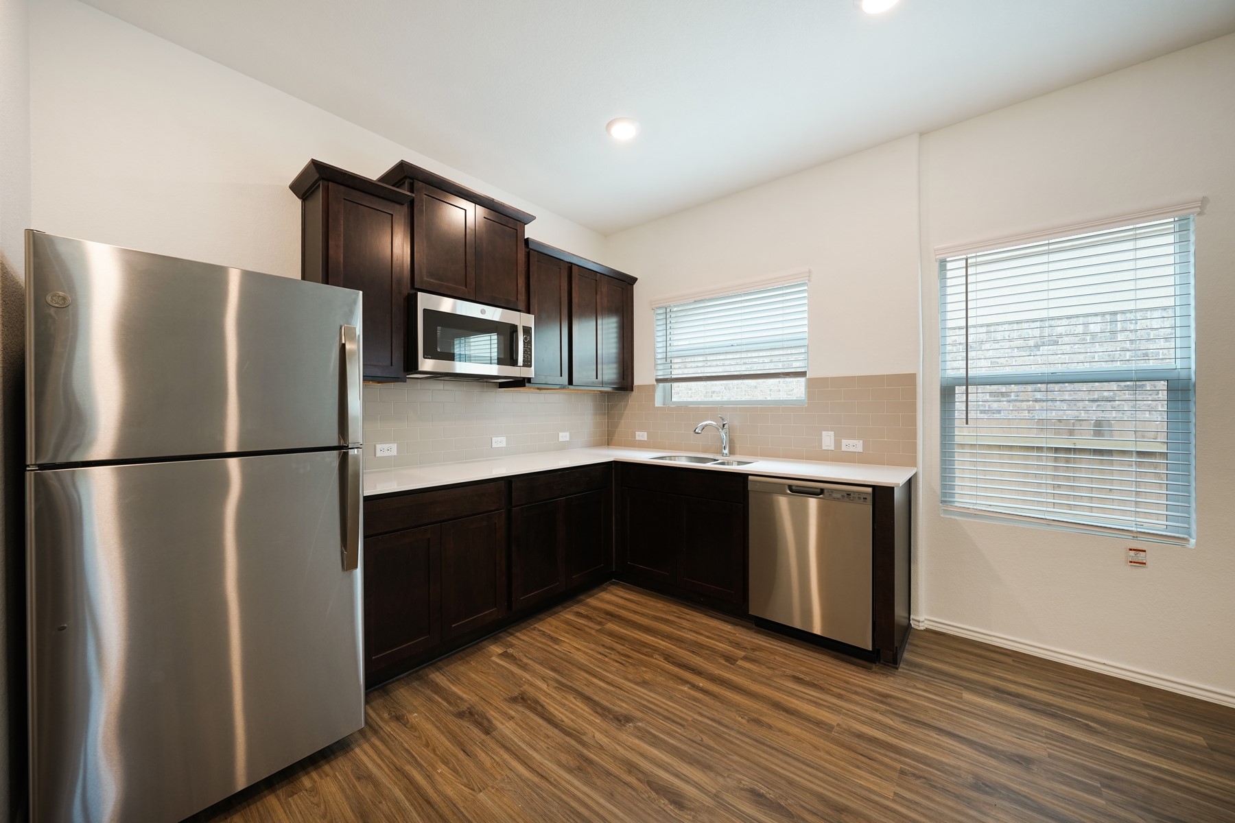 932 Mallow Road Leander, TX 78641 - Photo 5 of 34 A well-appointed kitchen showcasing contemporary dark wood cabinetry and integrated stainless steel appliances.